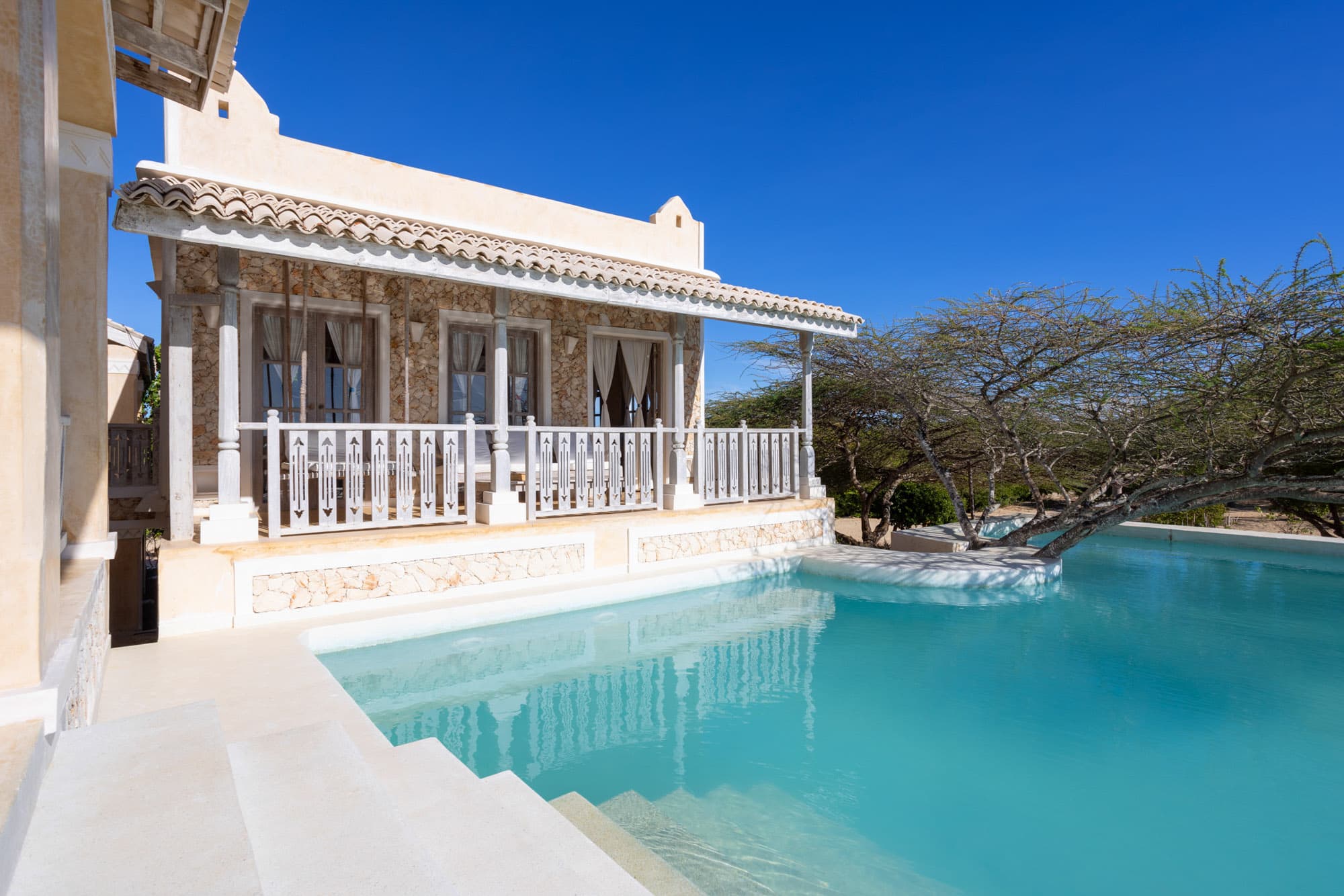 Pool and exterior of Amani House under a clear sky